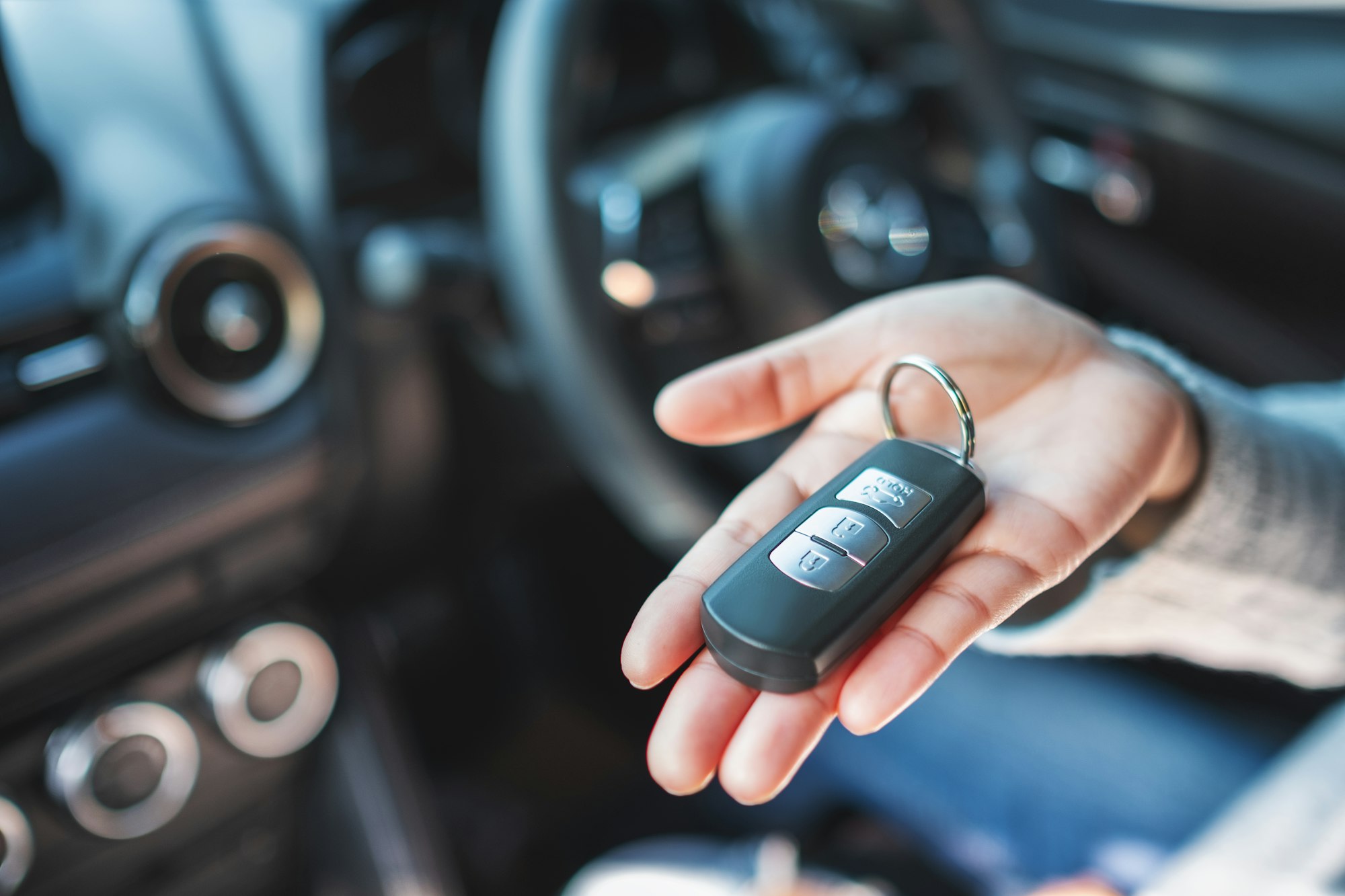 A woman holding and showing car key while sitting in the car