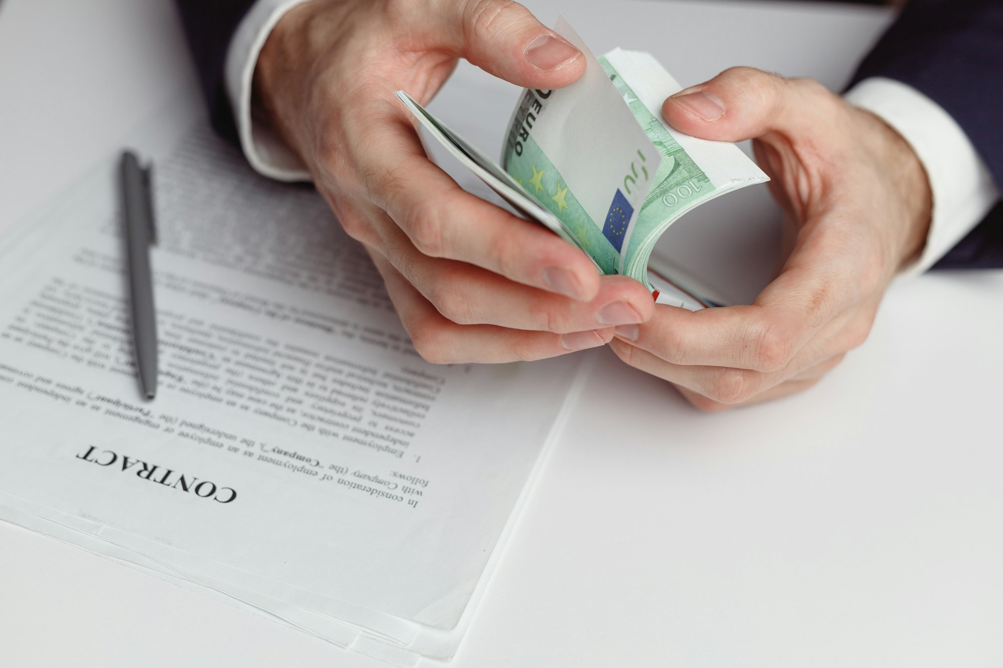 Man in suit counts wad of money before signing contract. Close up of hands with money